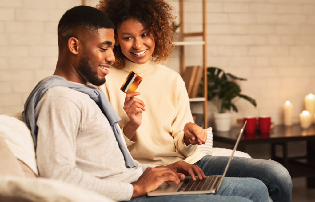Happy spouses shopping online on laptop, ordering new clothes at home